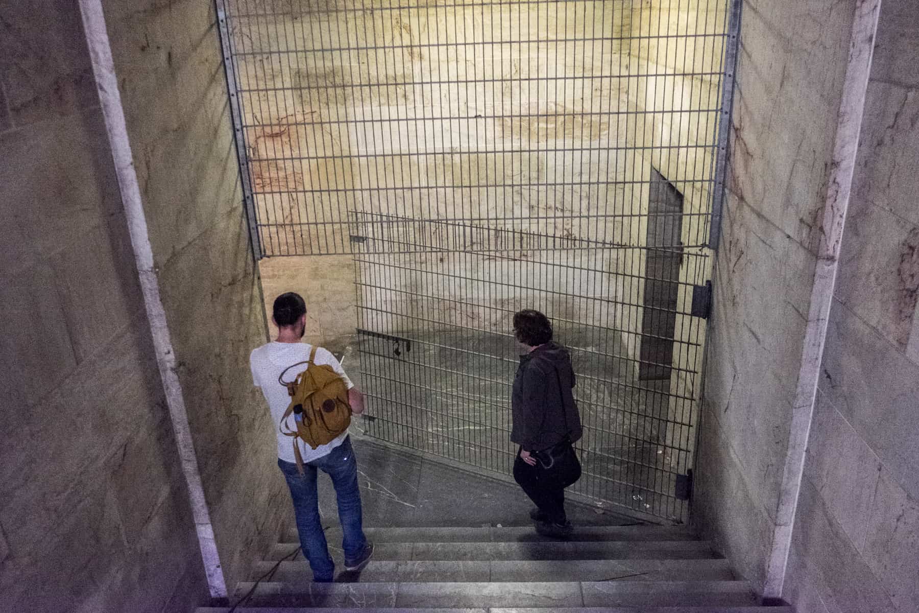 A man and a female tour guide walk through the looming marble interior of the Zeppelin Field Tribune building - one of the Nazi Party Rally Grounds sites