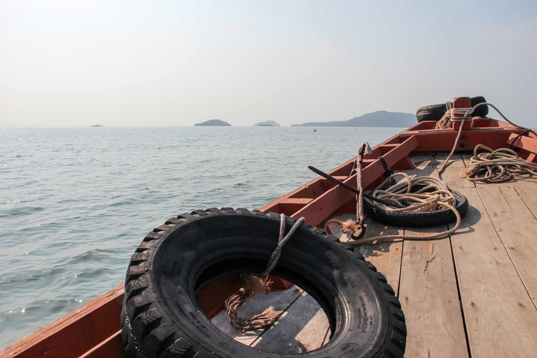 A wooden boat with black tyres as floats heading towards Rabbit Island in the background