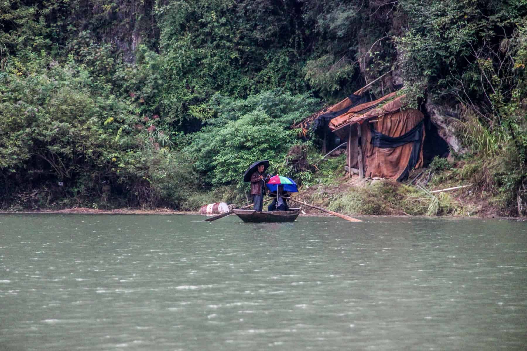 Two Chinese men on a small wooden boat on the Yangtze River while its raining