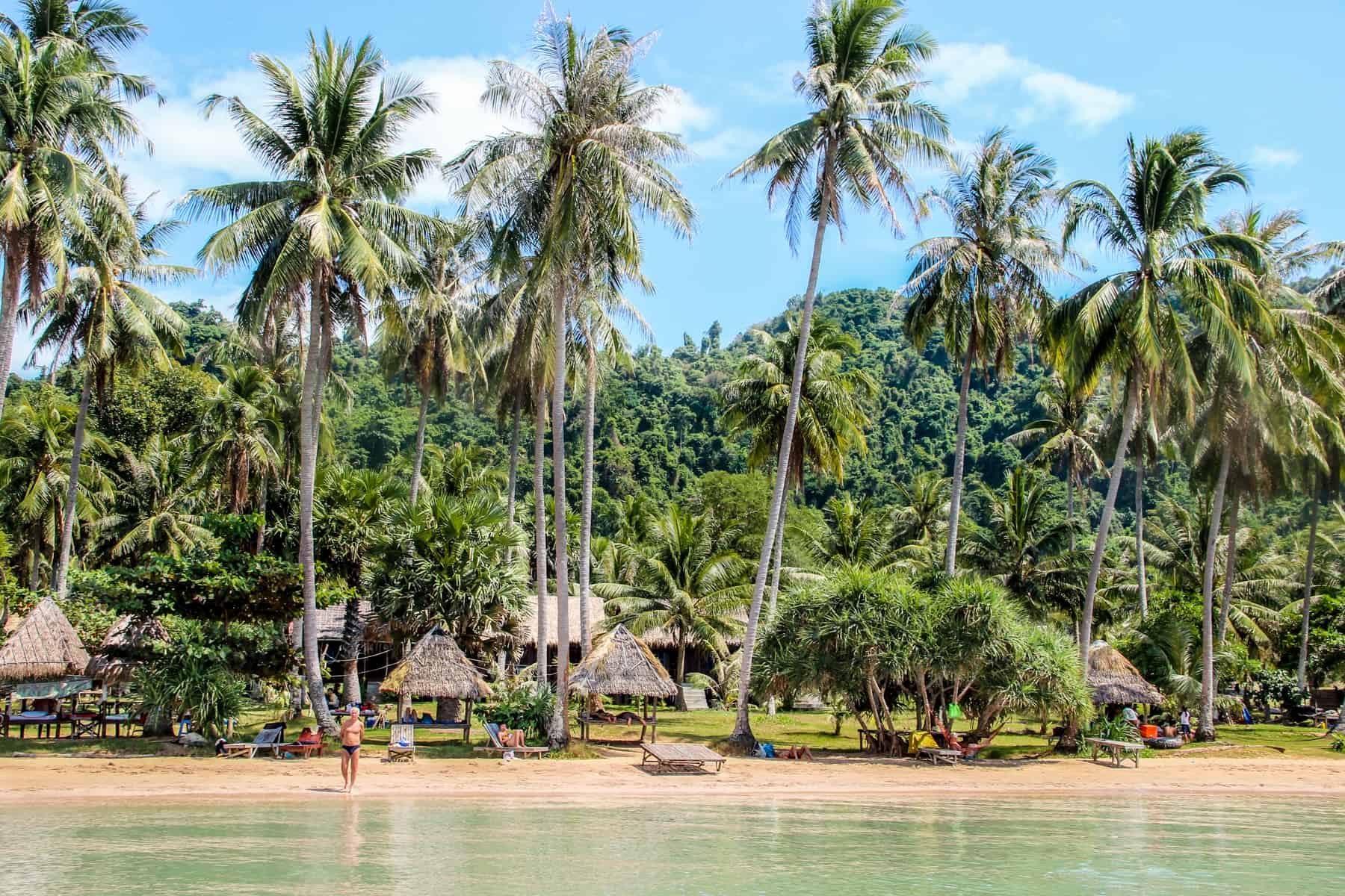 The wooden hut and palm tree lined and jungle backed sandy coastline of Rabbit Island Cambodia