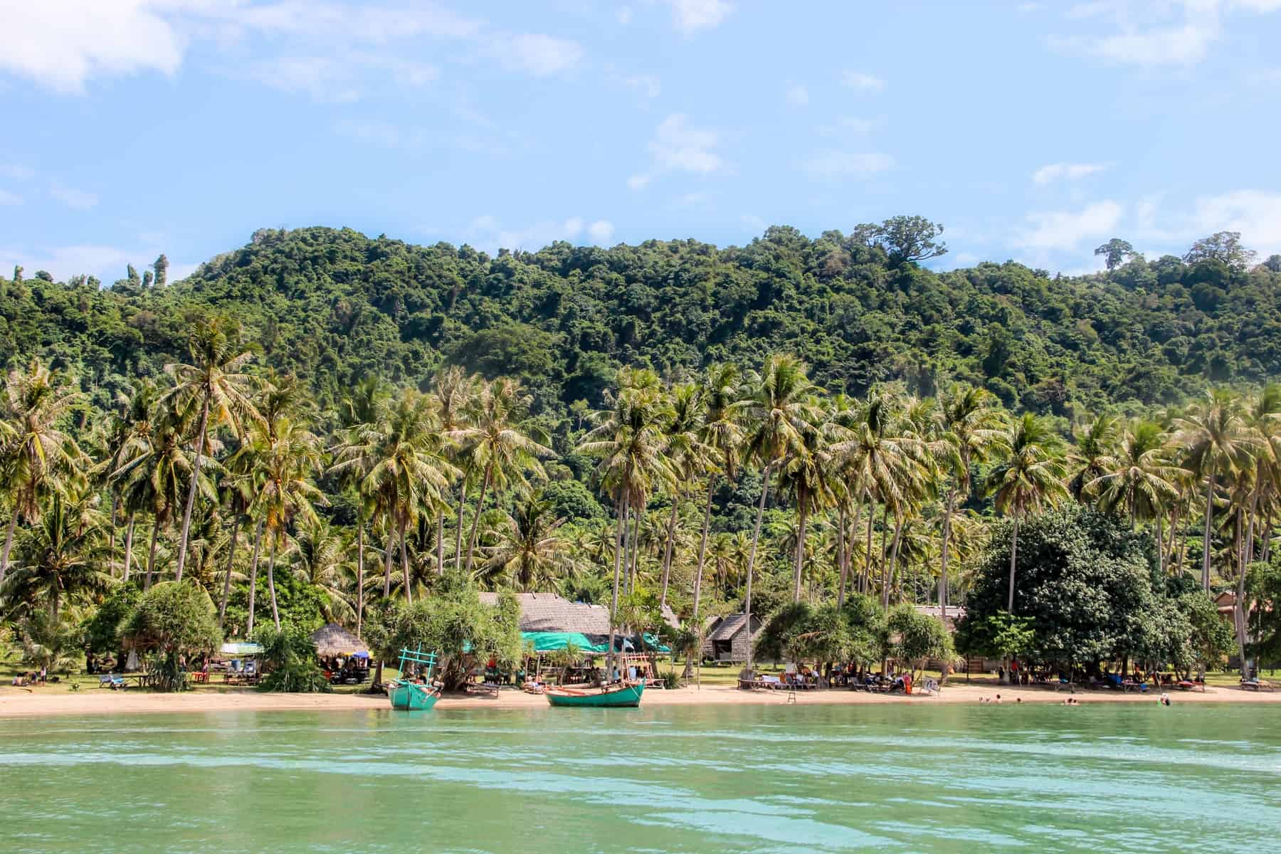 The emerald green waters a nd yellow sand beaches in front of the dense forest filled Rabbit Island in Cambodia