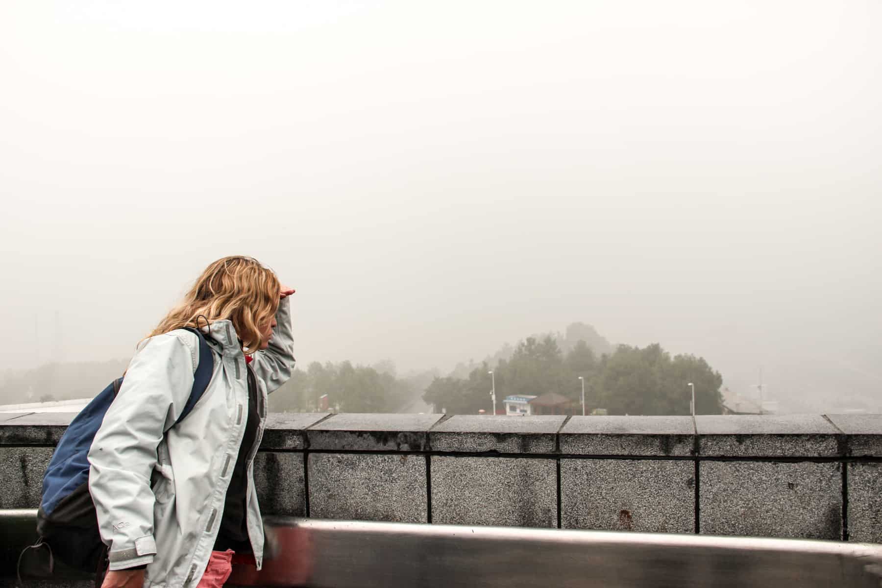 A woman looks out to a view of dense fog, trying to see the Three Gorges Dam in China