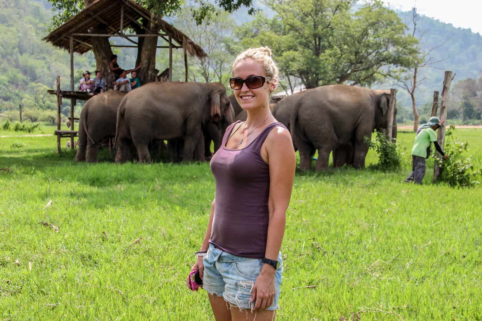 A tourist visiting elephants in Thailand, standing in the green of the conservation Elephant Nature Park in Chiang Mai, Thailand.