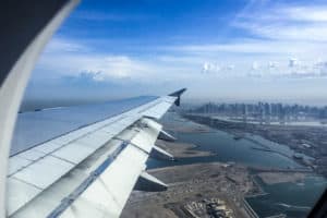 View from a plane window with the plane wing on the left and the city coastline of Australia on the right.