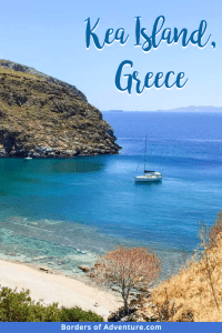 A small white boat floating on the bright blue waters on the sandy, rocky cove coastline of Kea Island in Greece