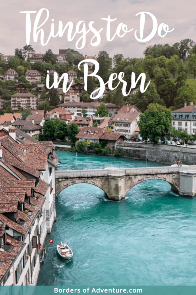 A view of the bright, turquoise Aare river in old Bern, Switzerland, seen from a elevated view overlooking the red-roofed Medieval buildings that line it