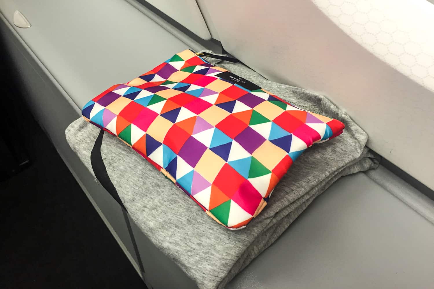 A multicoloured wash bag on top of a grey pair of pyjamas - the Qantas Business Class Amenity Kit.
