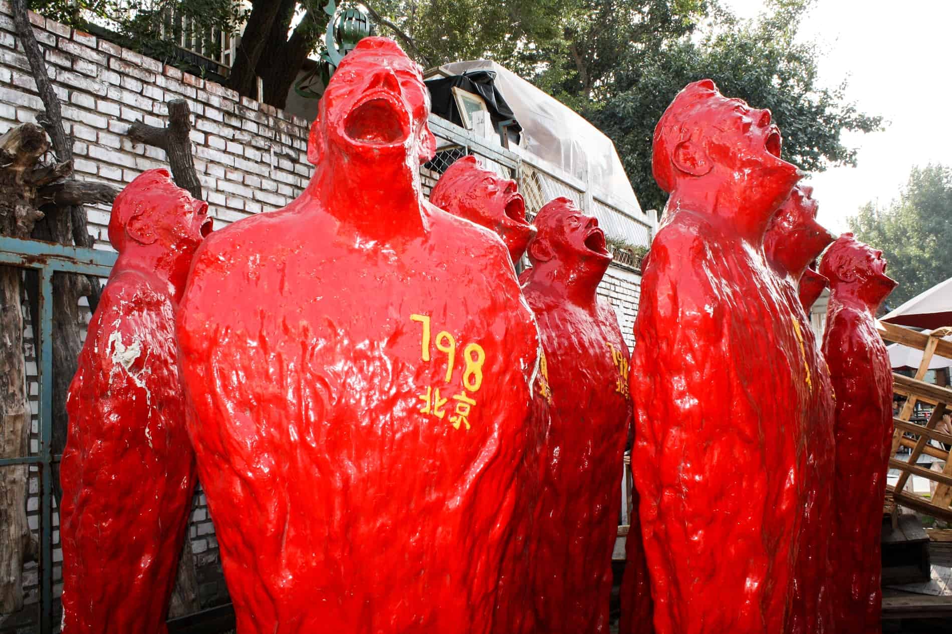 8 red sculptures of men screaming with yellow numbers and chinese characters in their chests. 