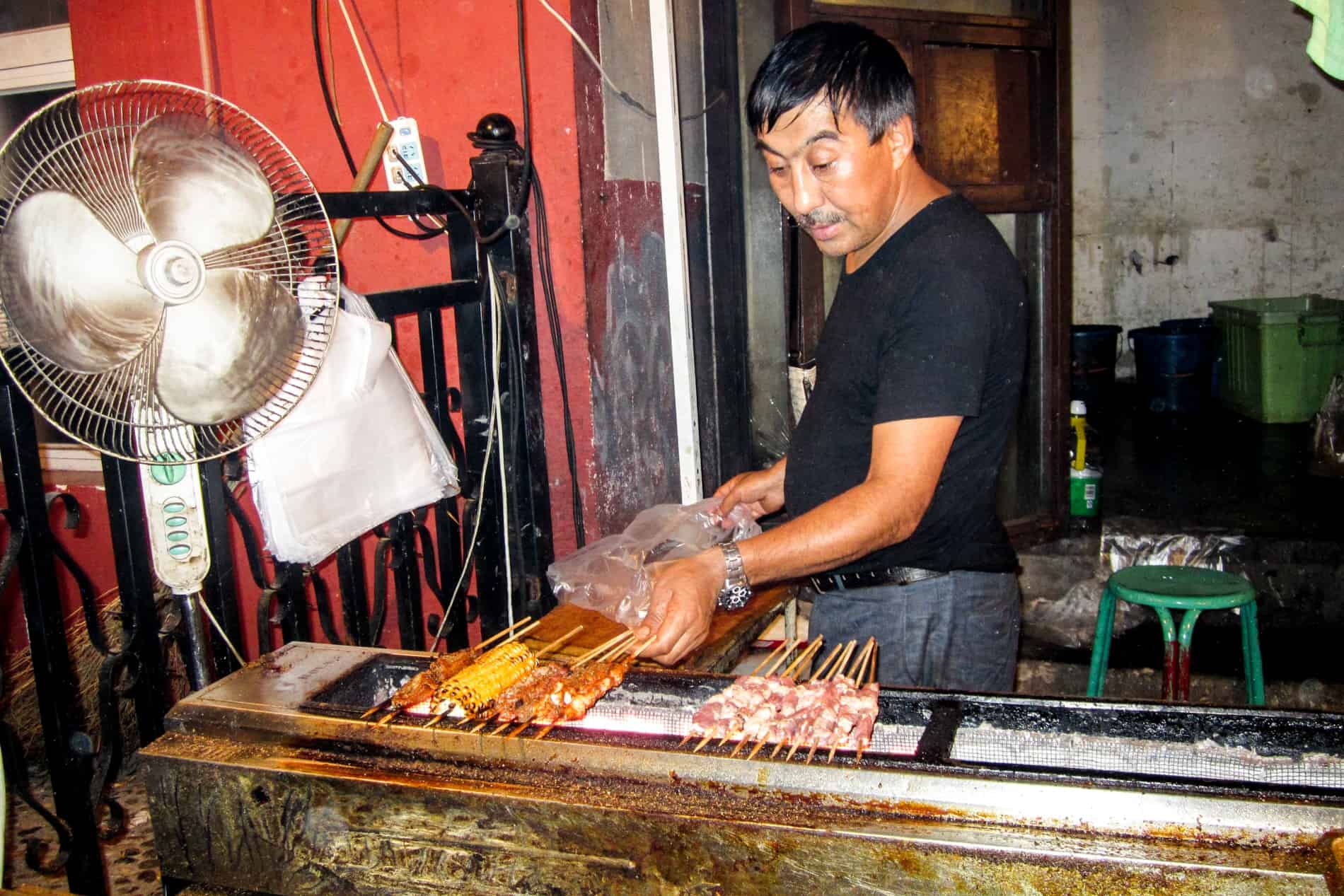 A Chinese man puts meat skewers on a grill at a night street food stall in Beijing. 