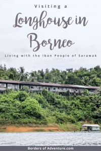 Distant view of a wooden Longhouse in Borneo built within the dense jungle next to the river