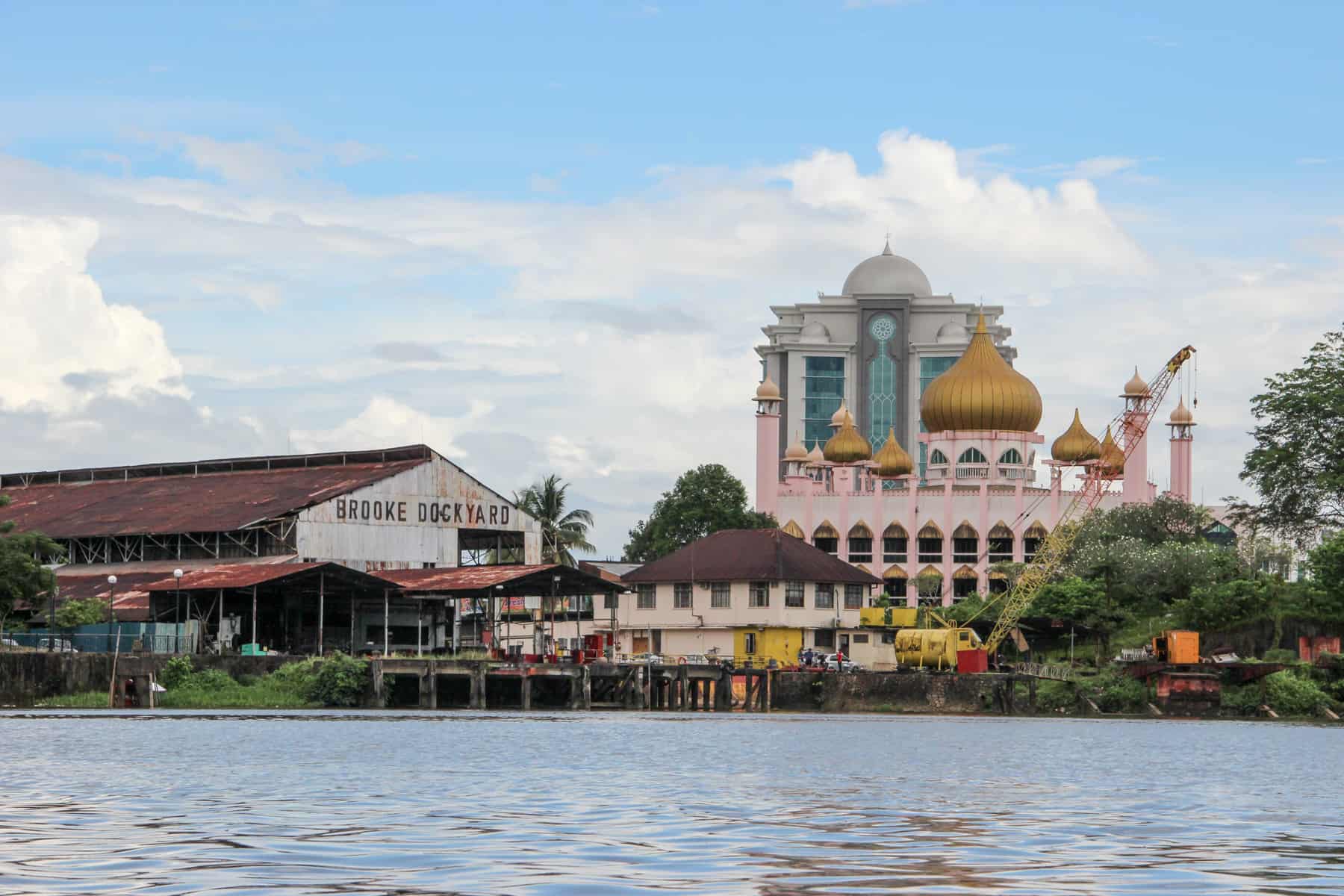 The historical attractions in Kuching sit on the riverfront and include the timeworn brown timber Brookes dockyard on the left and the pink painted, gold-roofed State Mosque on the right