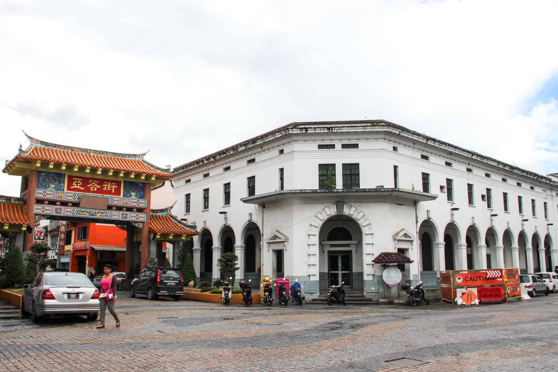 The long white multi-windows and archways of the Main Post Office building in Old Kuching, that sits to the right of a Chinese style doorway