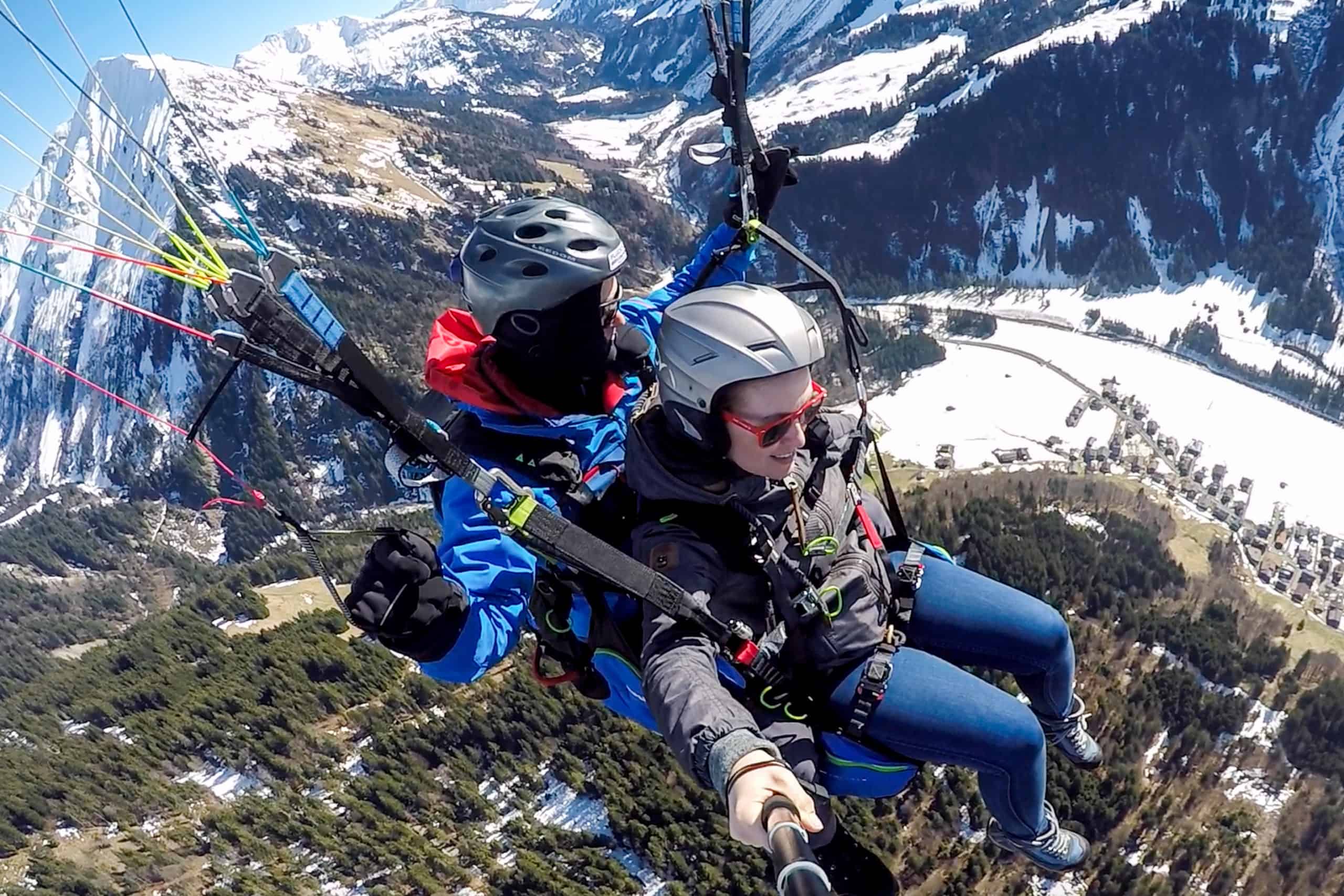 A woman tandem paragliding in Austria with a male pilot over a Vorarlberg valley