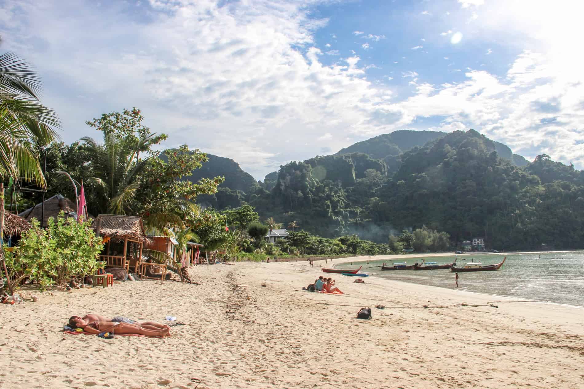People sunbathing on a jungle backed beach in Krabi, Thailand. 