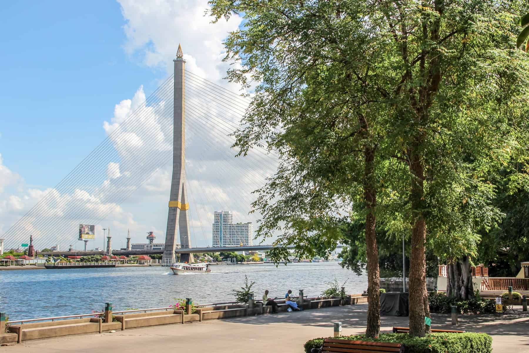 the tall, grey and yellow needle type structure of the rvercrossing Rama IX Bridge in Bangkok, Thailand