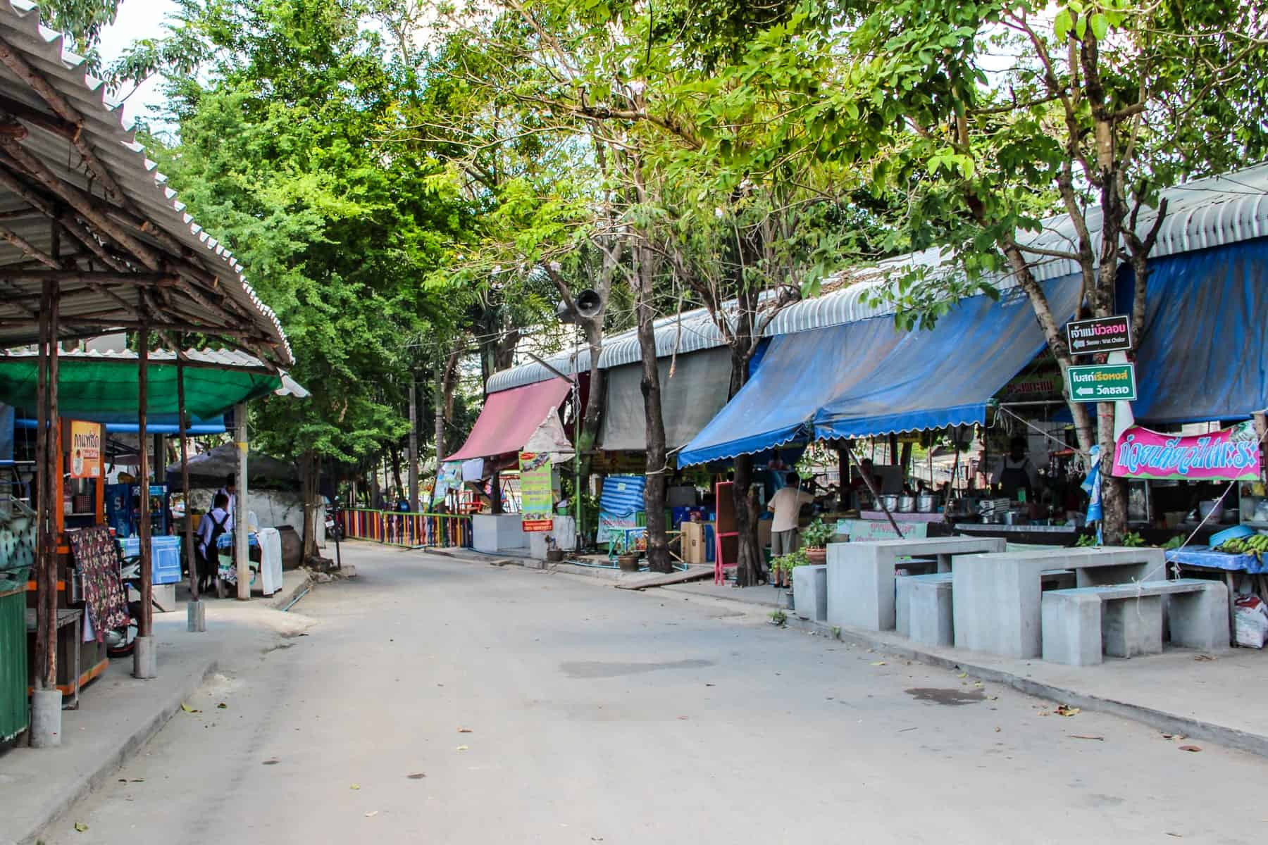 Street side marketplace stallswith blue and pink raincovers in rural Bangkok