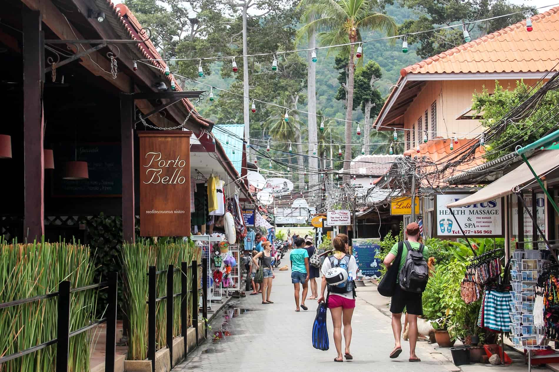 A busy pedestrian street with a jungle backdrop, on the Thai island of Koh Tao.