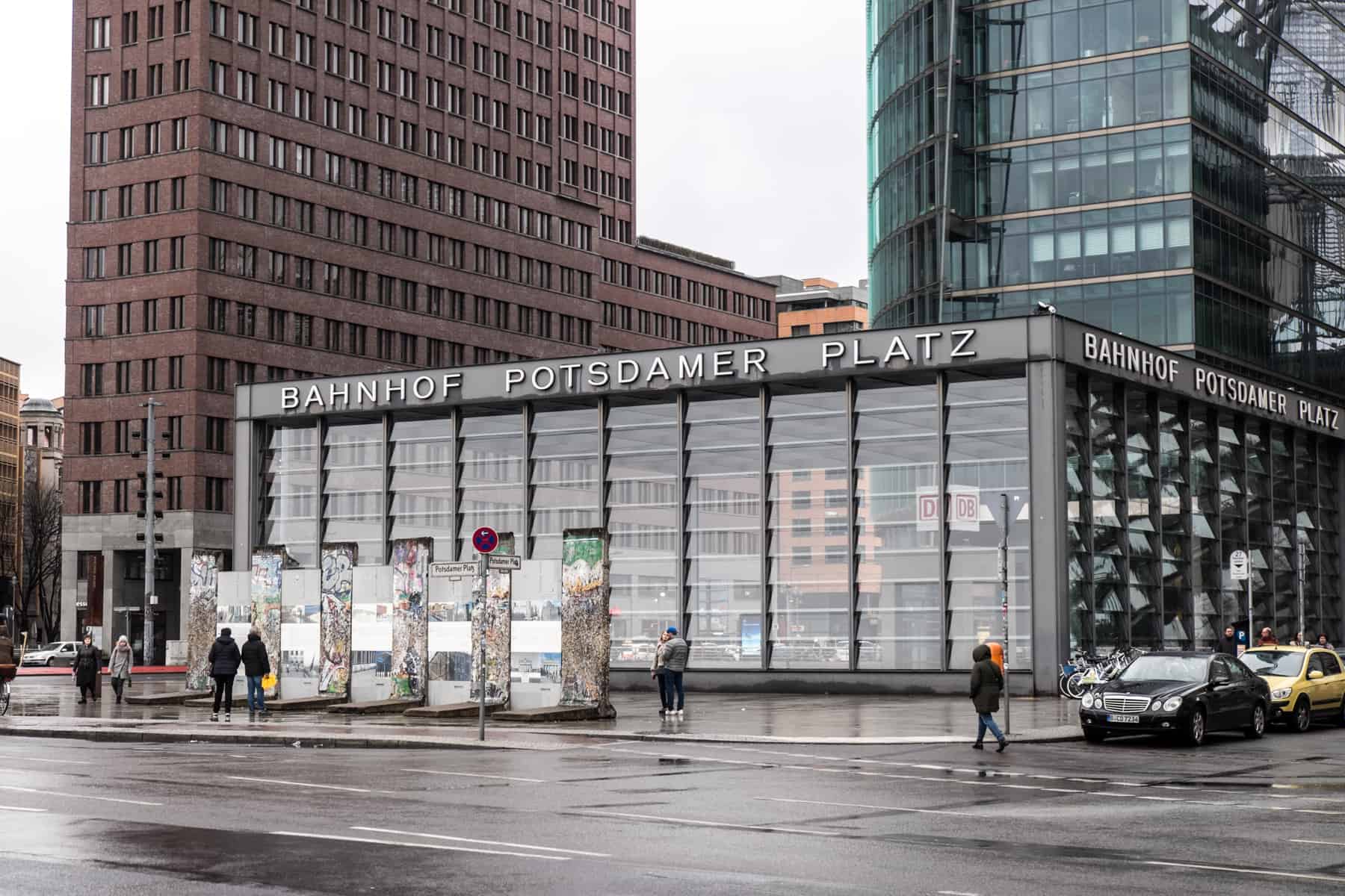 Six sections of the Berlin Wall stand outside the glass box rail station of Potsdamer Platz in front of high rise buildings