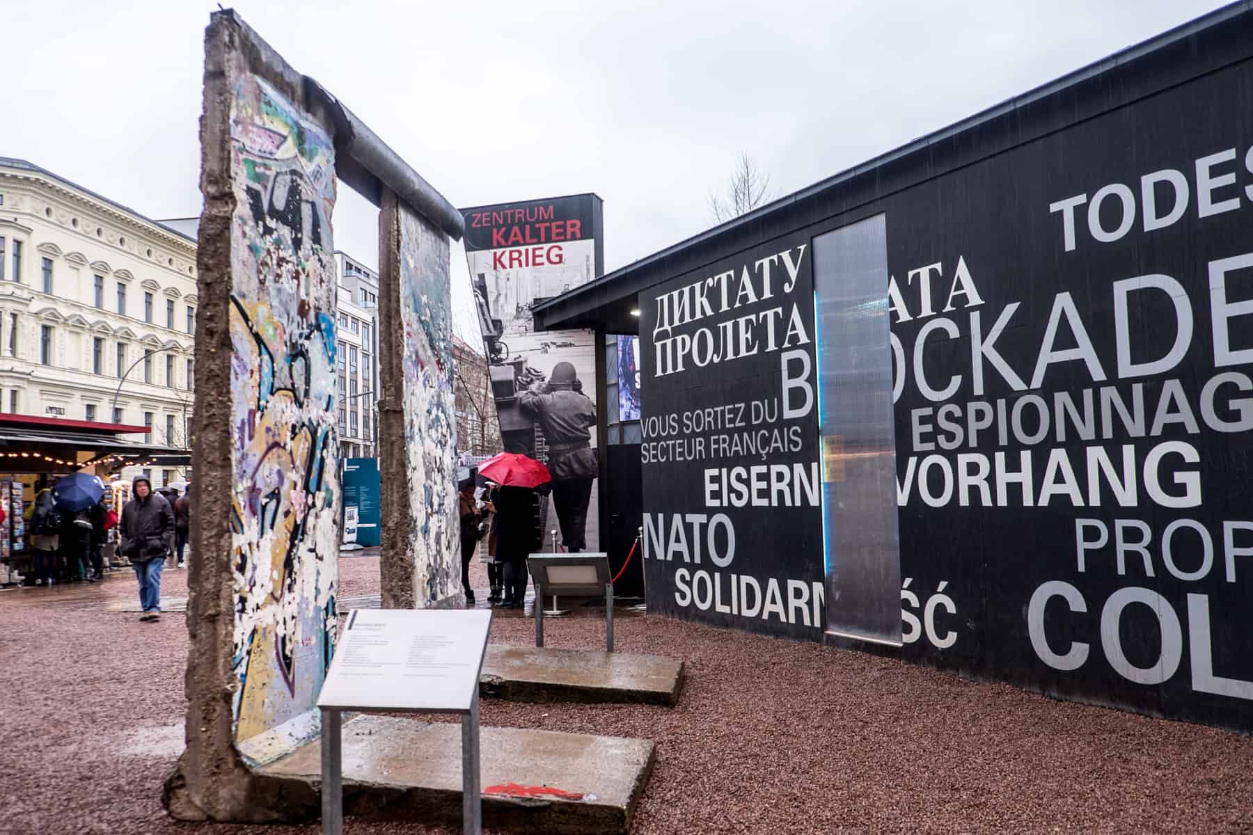 Two slabs of Berlin Wall covered in graffiti stand next to a blackbox building as part of an exhibition in Berlin Germany