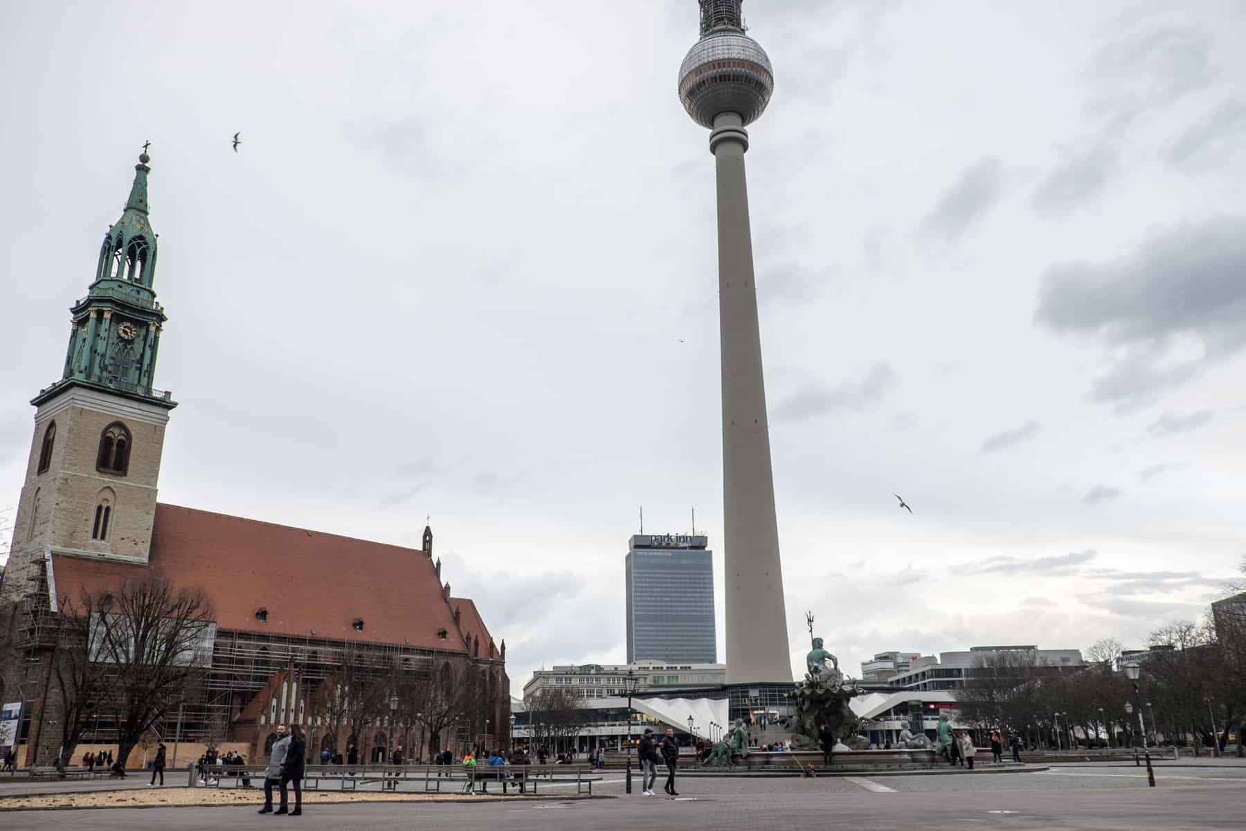 A church to the left and the TV Tower of Alexanderplatz in Berlin with the Park Inn hotel in the background