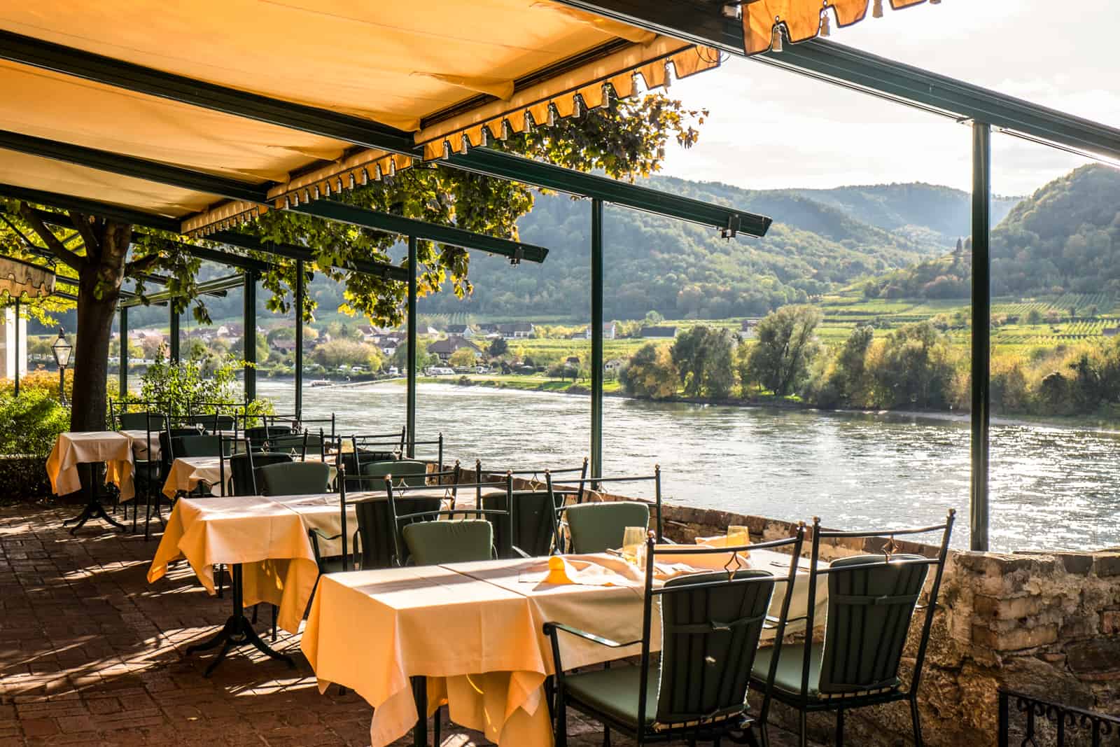 The green chairs and white tables in the Schlossberg Hotel Durnstein overlooking the Danube River and the surrounding green