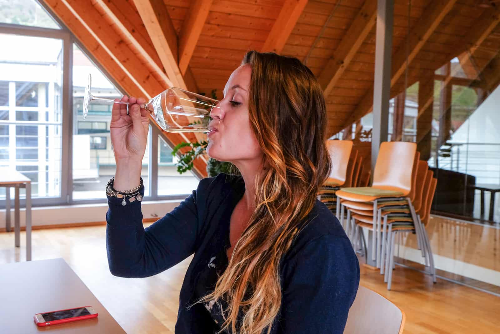 A woman wine tasting a white wine at the Domäne Wachau winery in a modern wooden decor building