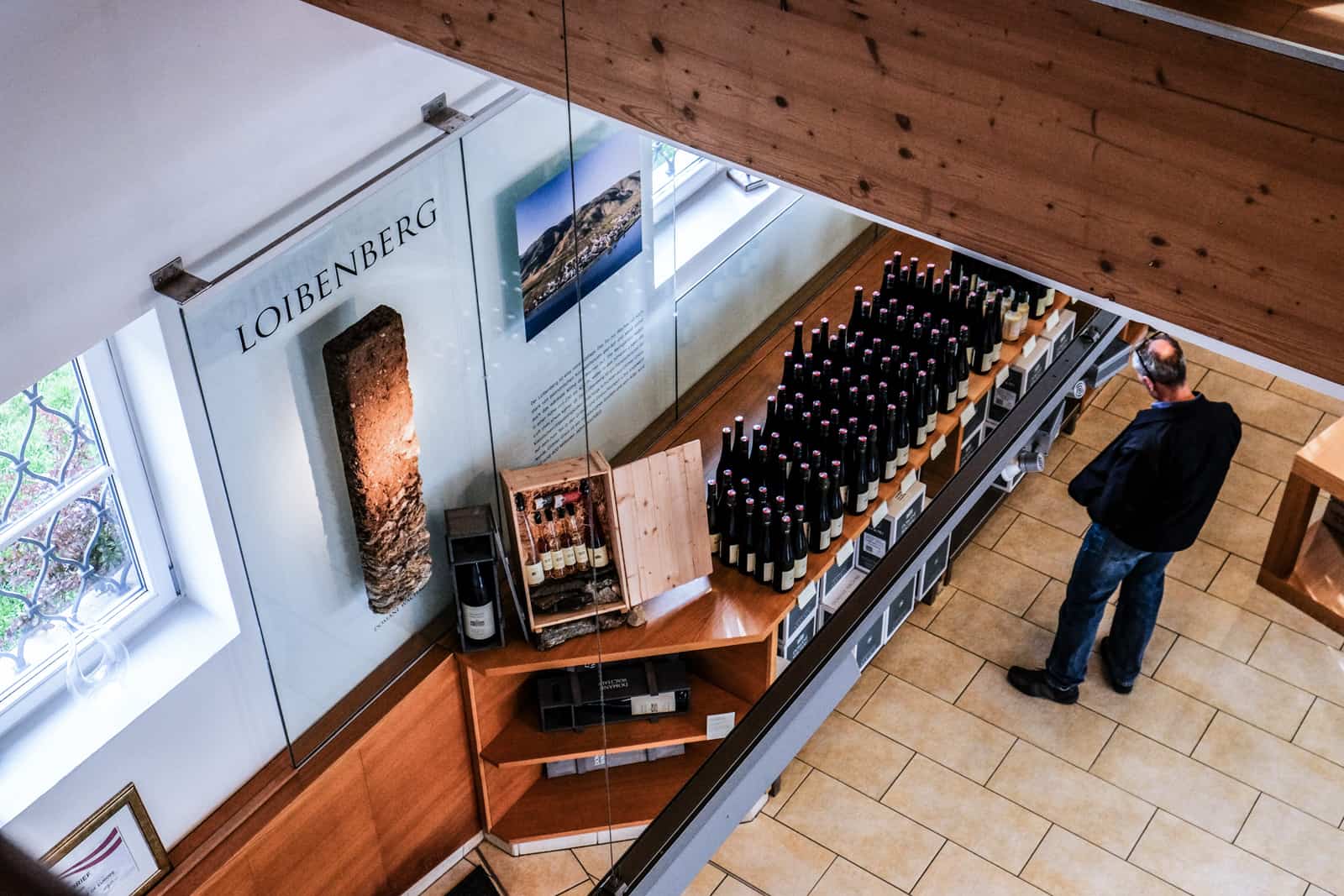 An elevated view of a man shopping rows of wine bottles at the Domäne Wachau winery shop