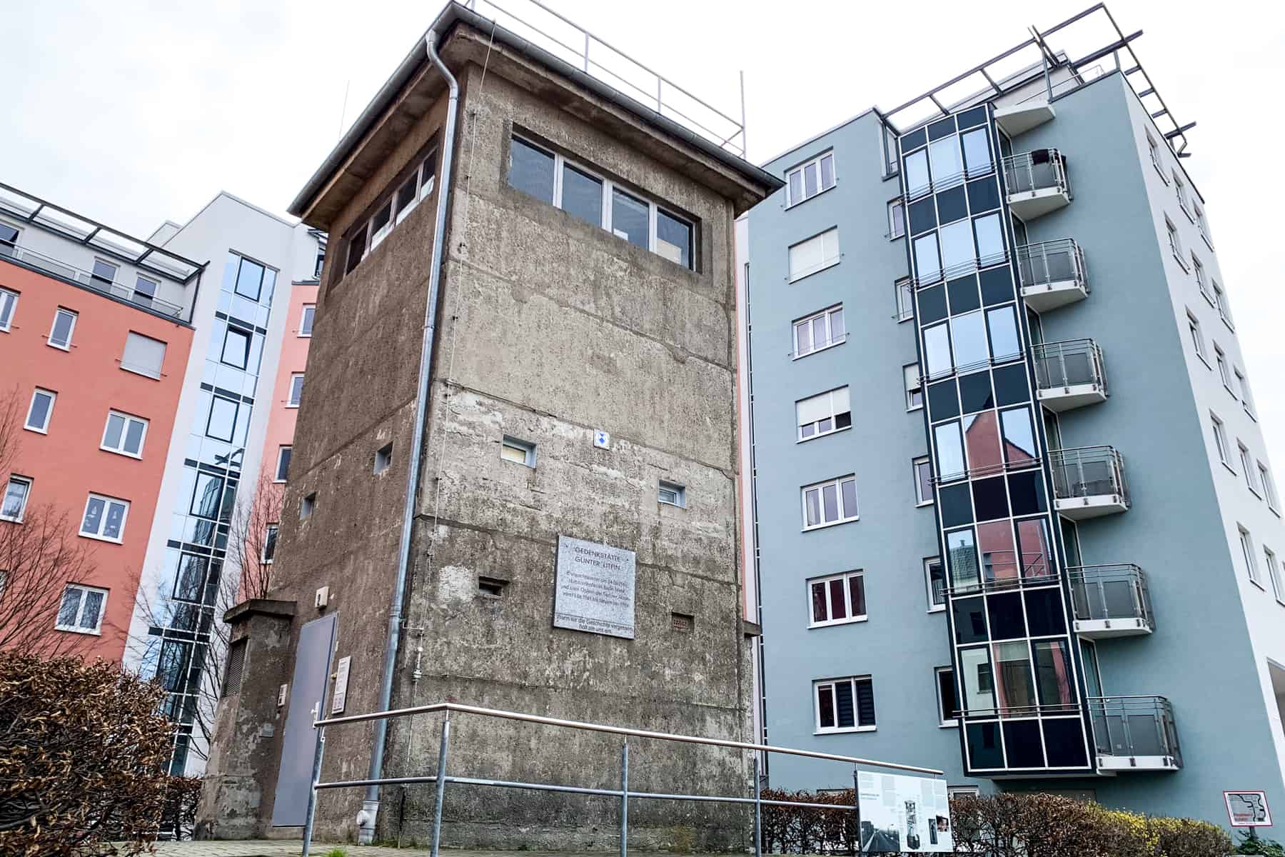 Günter Litfin Memorial is a preserved Berlin Wall Watchtower that stands in front of a modern orange and blue apartment building