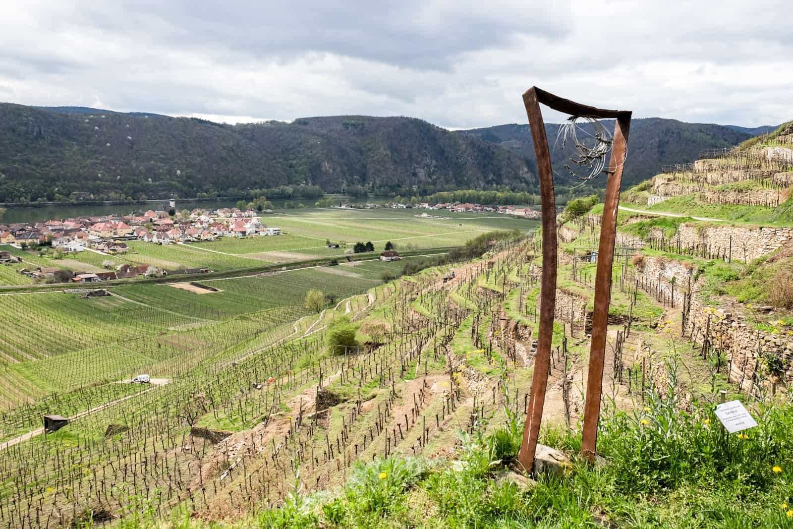 A squashed door frame shape metal art sculpture on The Wachau World Heritage Trail looking out over a slope of vineyard terraces