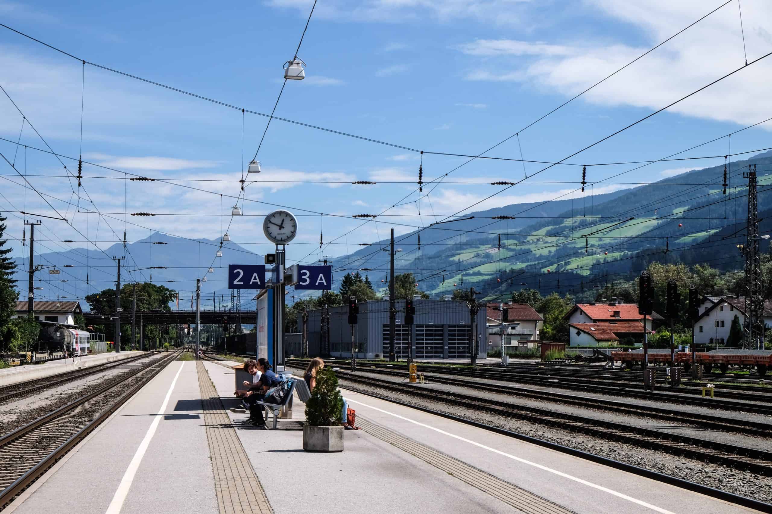 People sitting and waiting on a railway station platform at Innsbruck train station in Austria