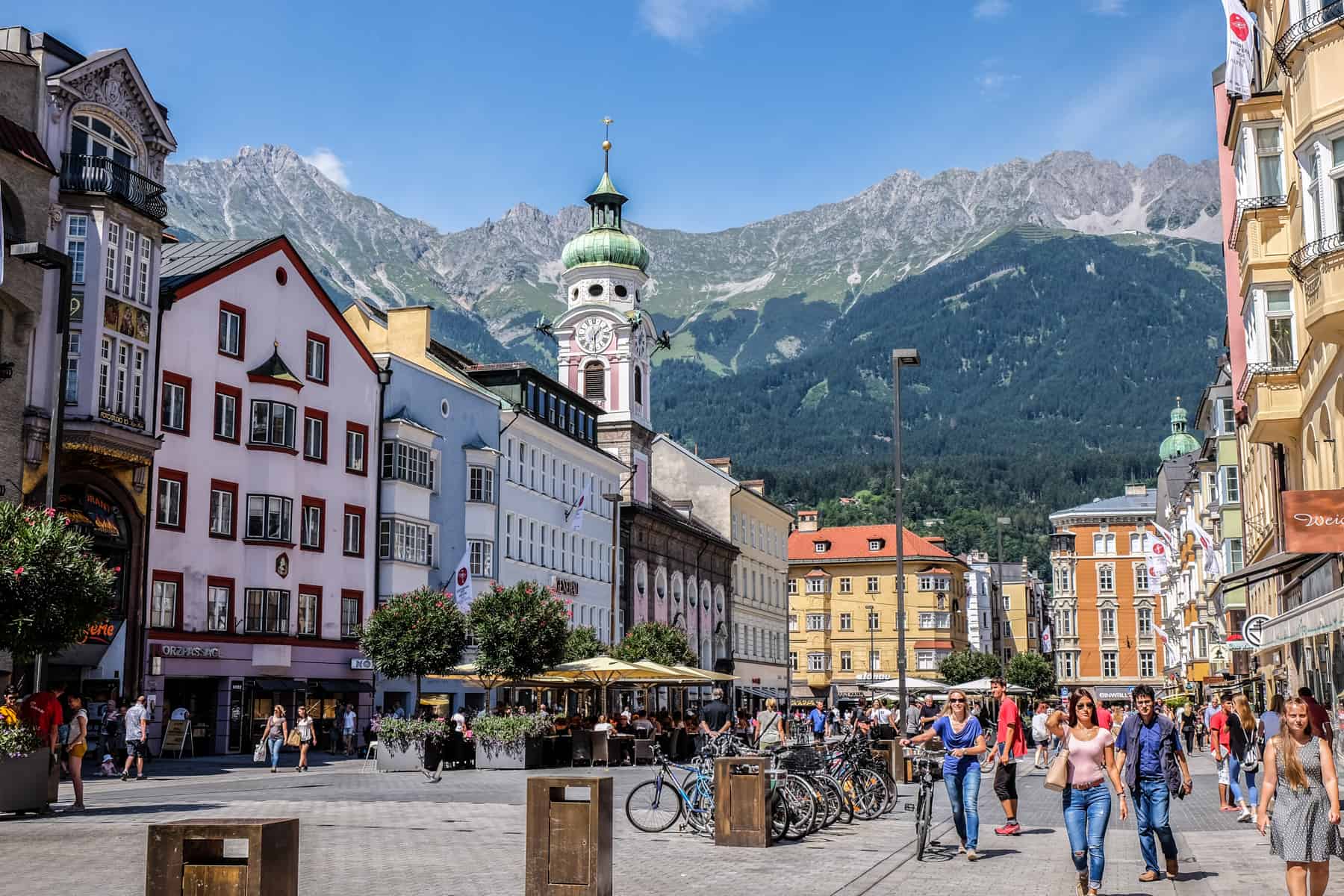 Main square in Innsbruck in Austria, filed with old pastel coloured buildings and backed by mountains