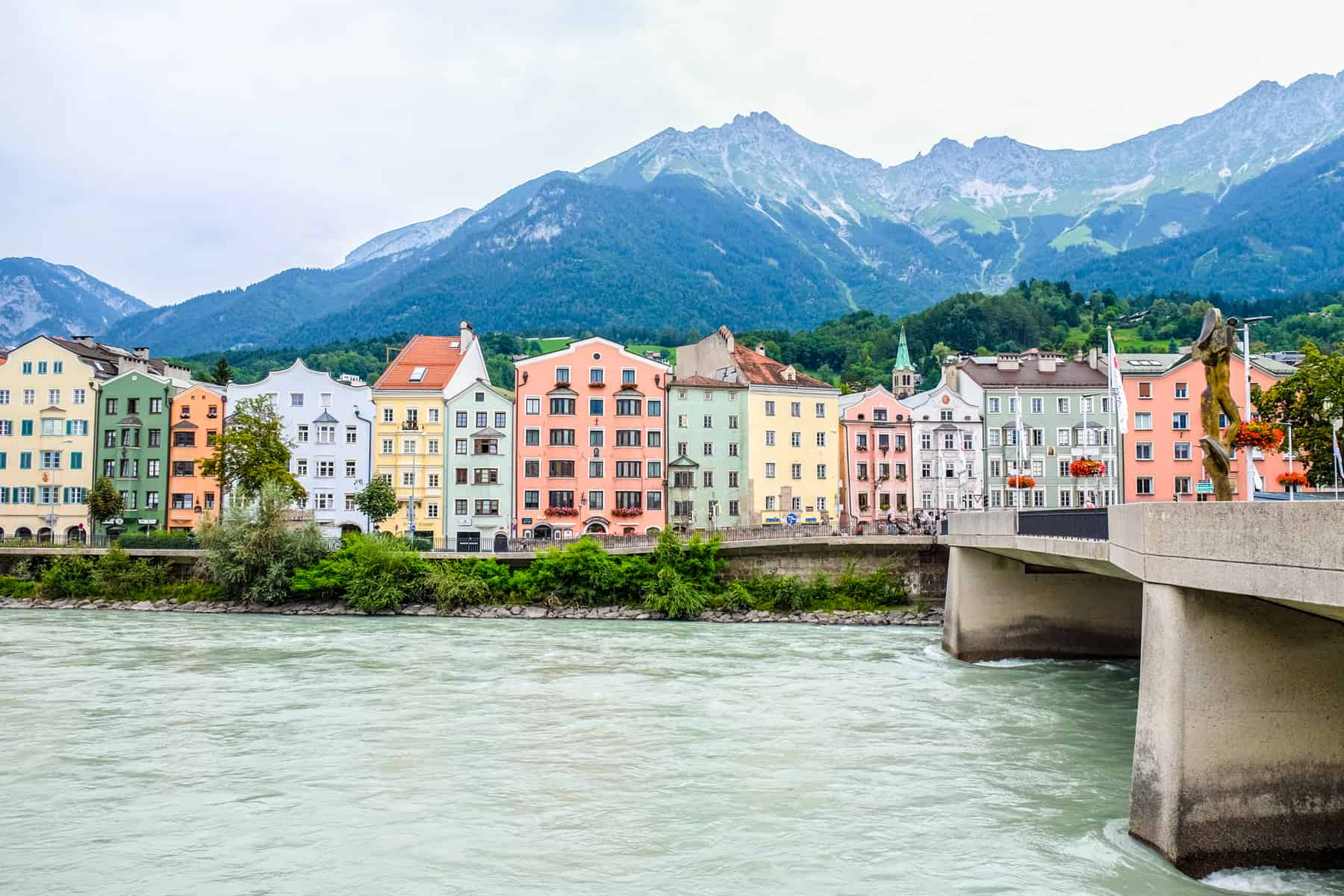 colourful houses along the Inn River in Innsbruck, to a backdrop of mountains.
