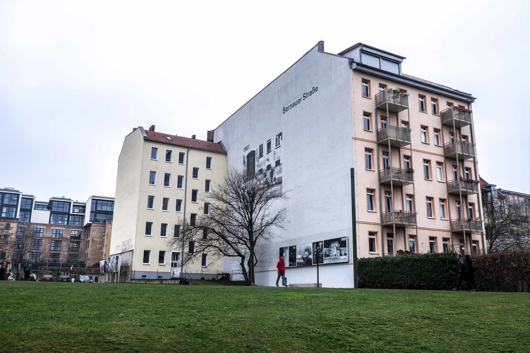 The grassy area that was a former Border Strip of the Berlin Wall and a wall house cover stating the street name – Bernauer Straße