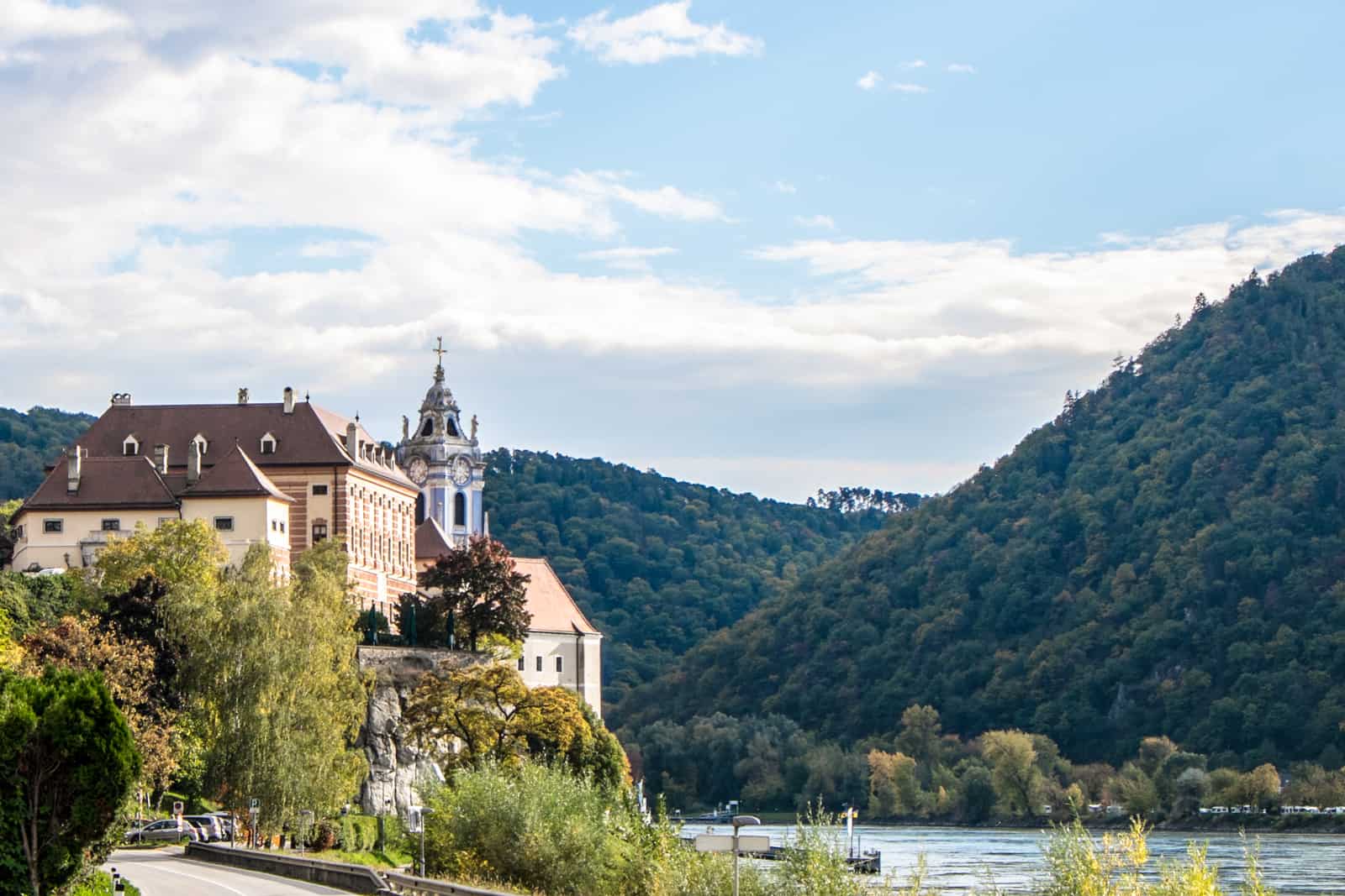 The large orange hotel building and blue church spire in Durnstein as seen from the road on approach to the town