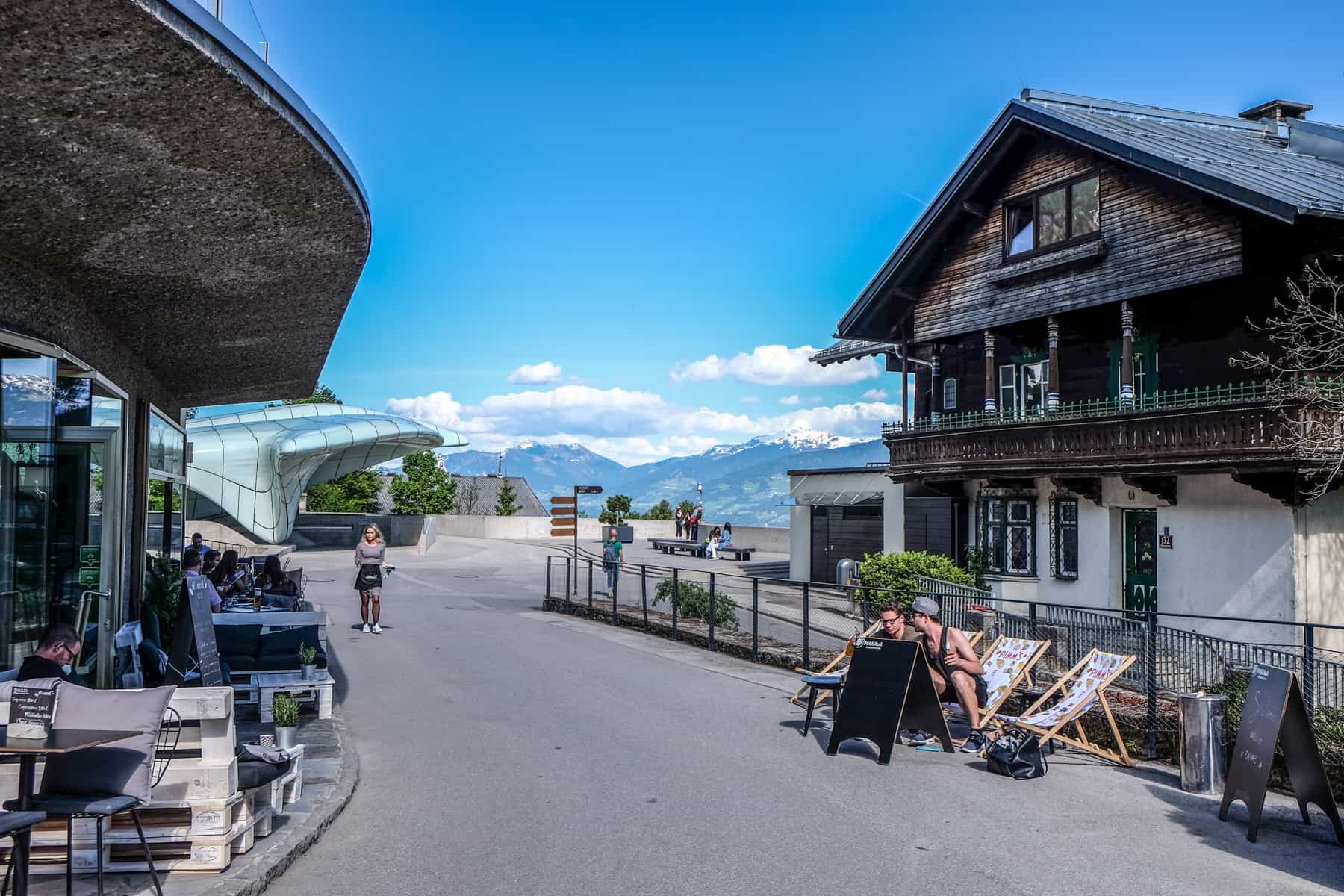 A modern cafe on the right and traditional wooden house on the left on the first level of the Nordkette Mountain in Innsbruck, Austria