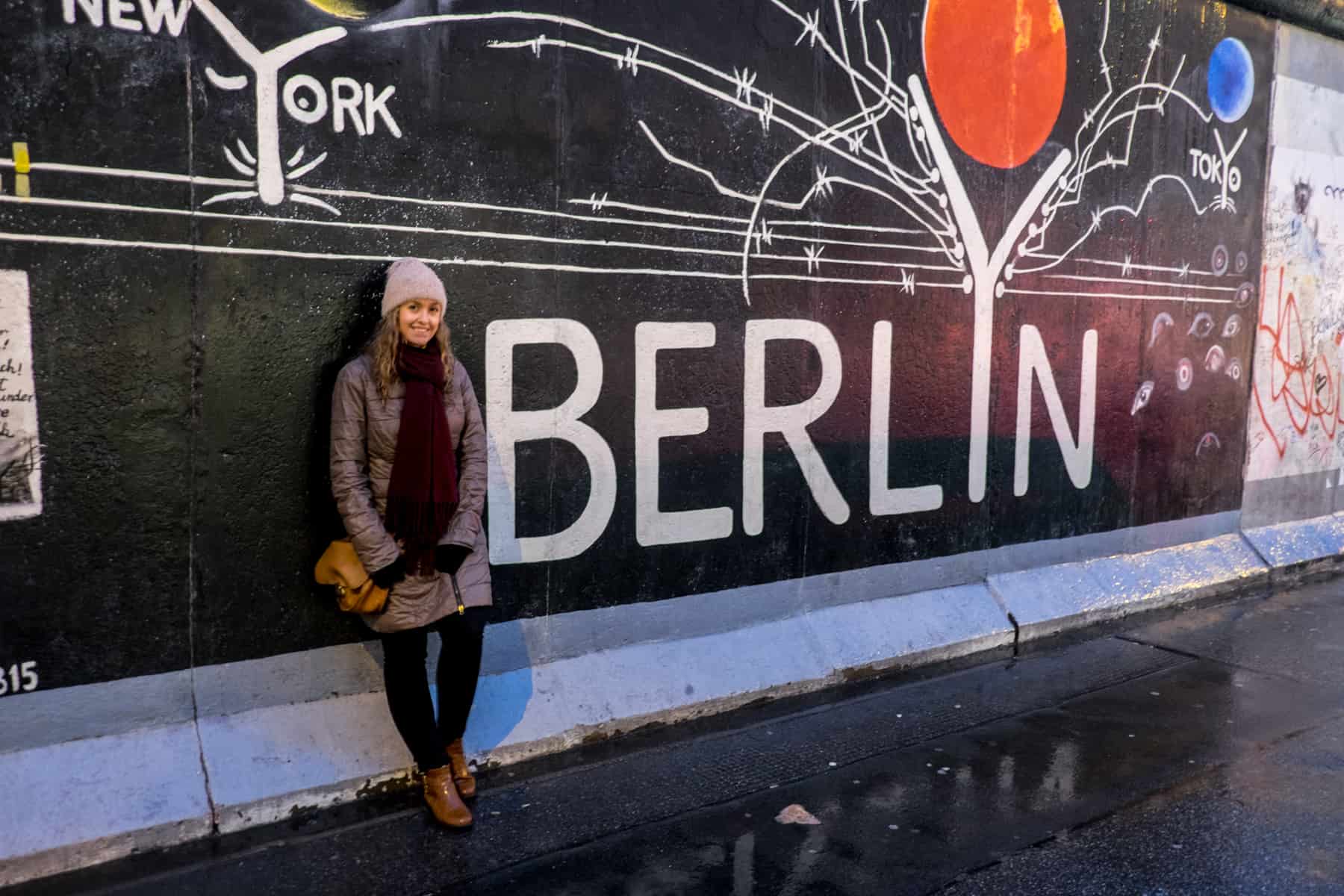 A woman stands in from the the Berlyn mural at the East Side Gallery Berlin Wall