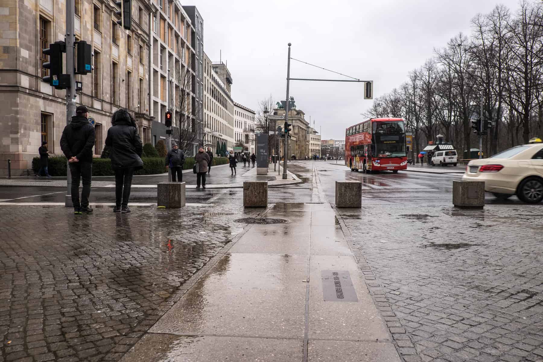 The area of Berlin with the Brandenburg Gate in the background and the row of double cobblestones on the street marking where the Berlin Wall stood, in the foreground