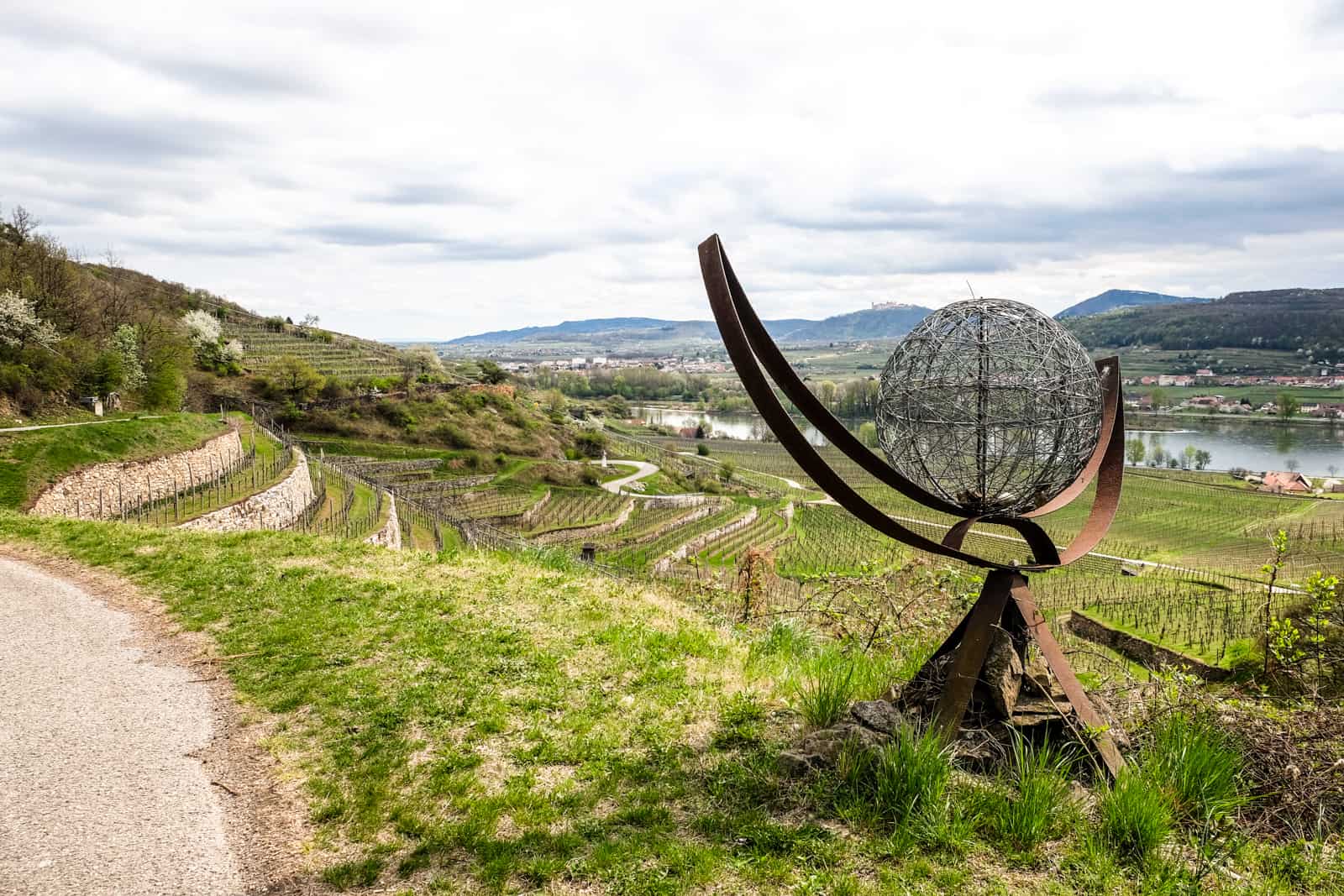 An art sculpture with a grey wire head and metal arms on The Wachau World Heritage Trail set in the terraced vineyard hills