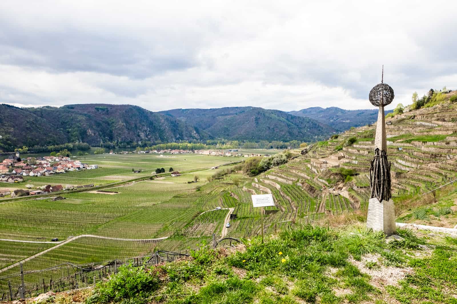 A spike piercing a ball art sculpture on The Wachau World Heritage Trail that stands like a pole in the sloping vineyard terraces overlooking a wide valley on the left