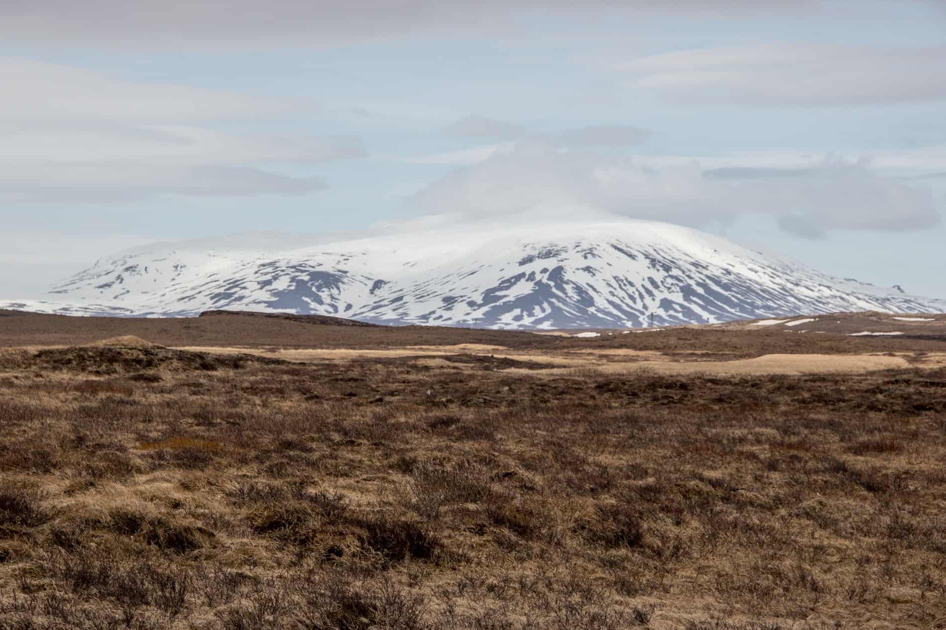 Sandy coloured barren land in Iceland in from of a snowcapped Blafell Mountain. 