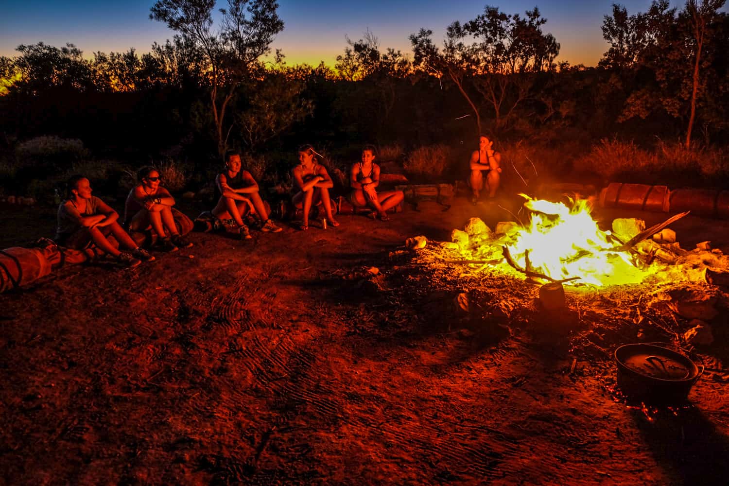Travellers sit on sleeping bags around a fire in the Australian Outback in the Northern Territory. 
