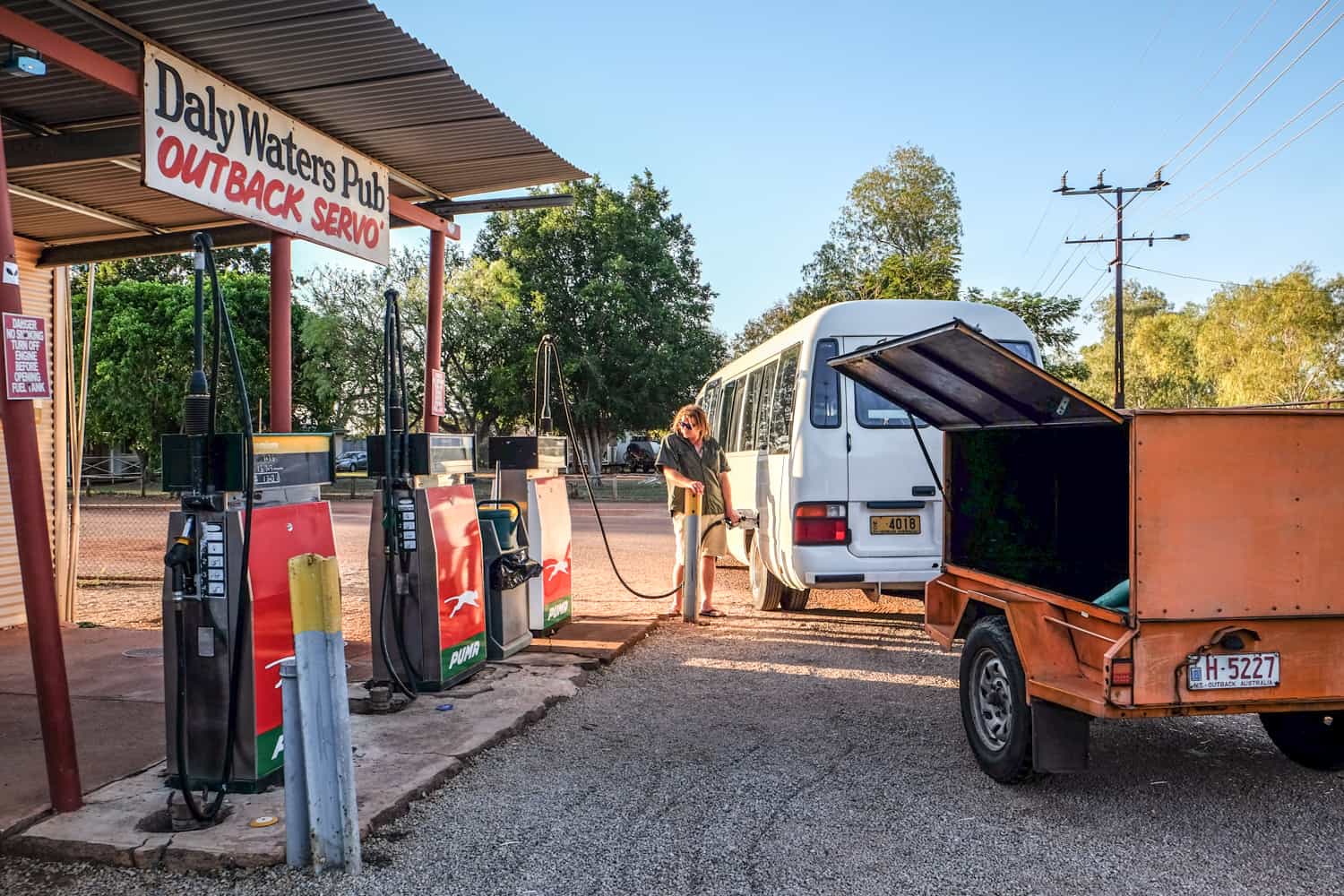 A man fills a white van with petrol at the 'Outback Servo' in Daly Waters Australia. 