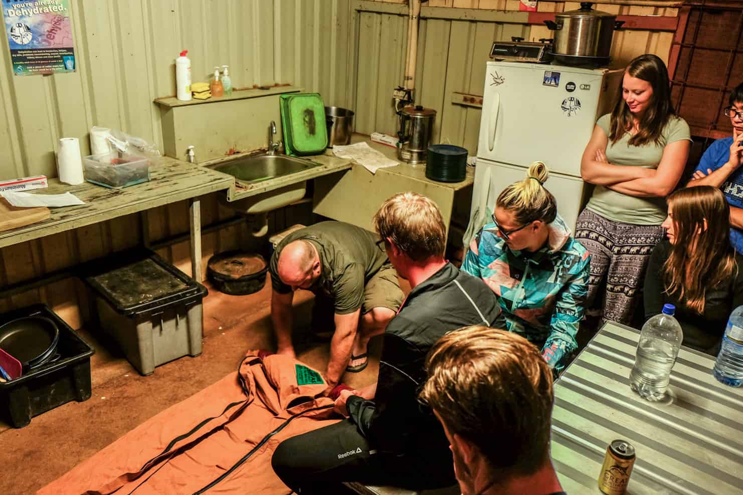 An guide shows a group of tourists how to use a Swag sleeping bag at a camp in the Australian Outback. 