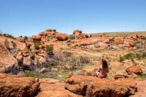 A woman sits within the formations of the Devil's Marble in the Northern Territory, Australia.