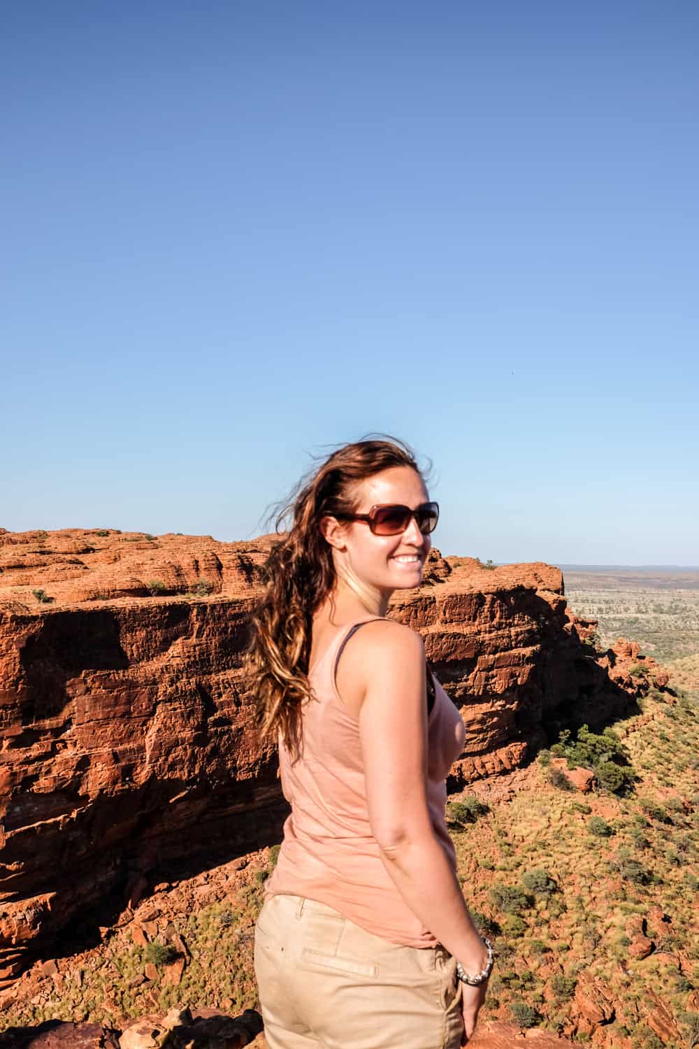 A woman looks back at the camera while standing at the top of Kings Canyon in Australia. 