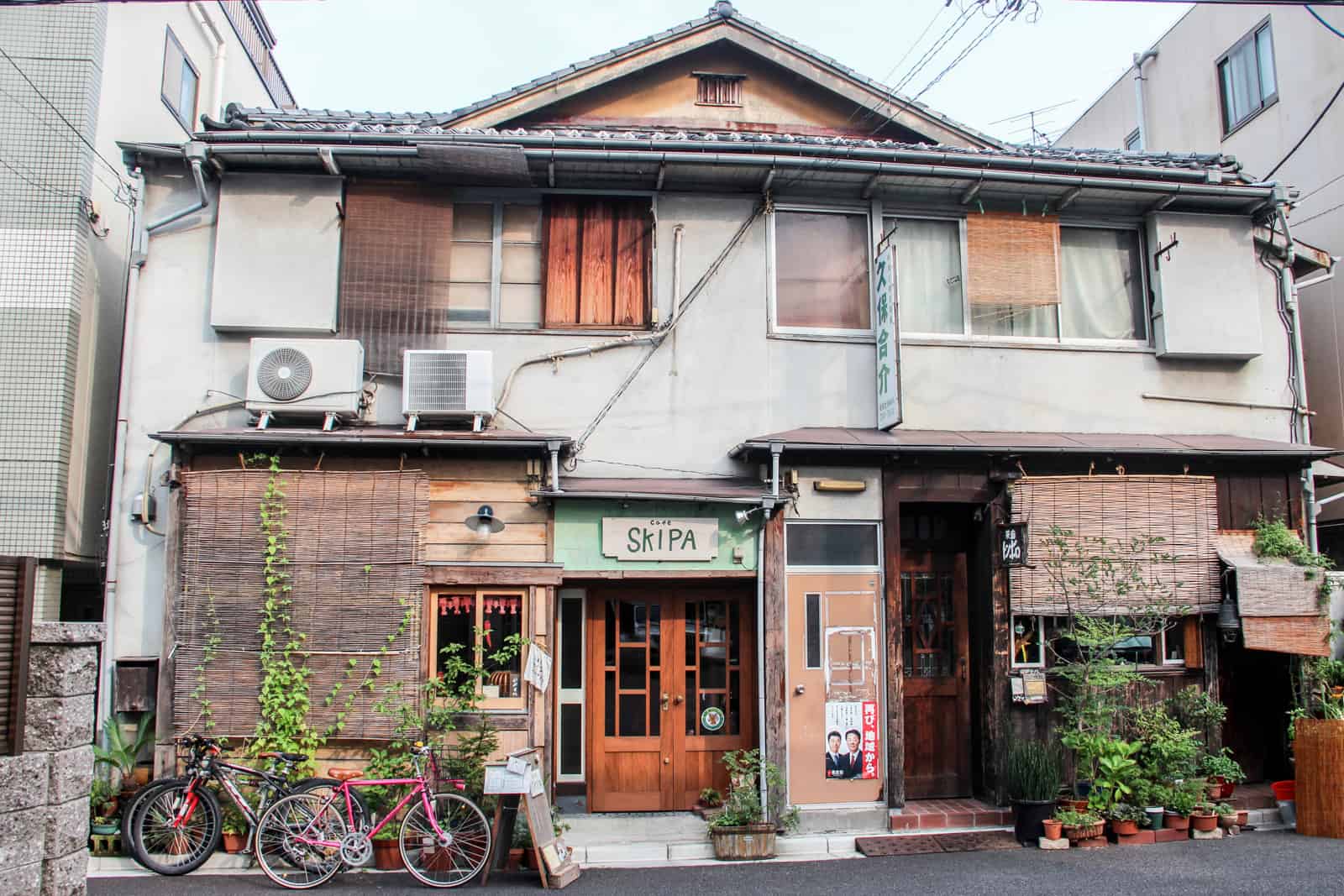 A traditional wooden house in Japan merged with a more modern white block building. 