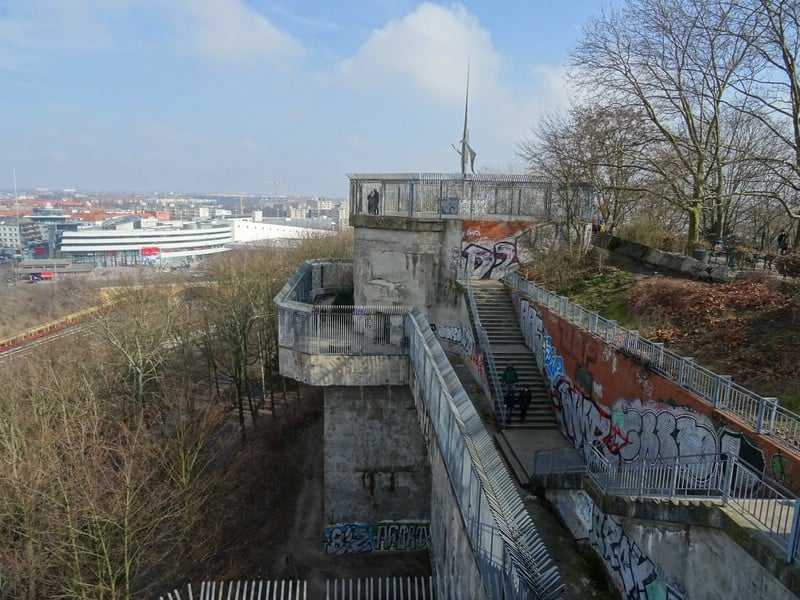 View from the top of a concrete tower covered in graffiti, overlooking Berlin city. 