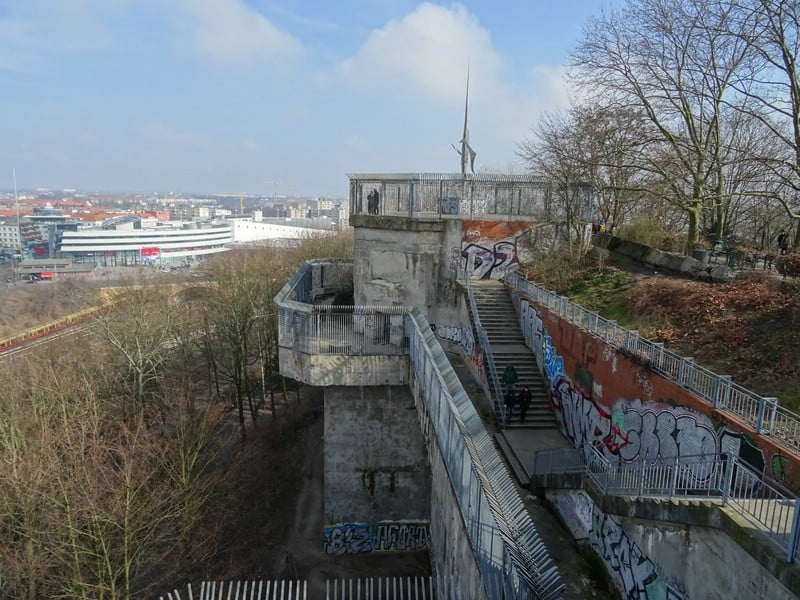 View from the top of a concrete tower covered in graffiti, overlooking Berlin city. 