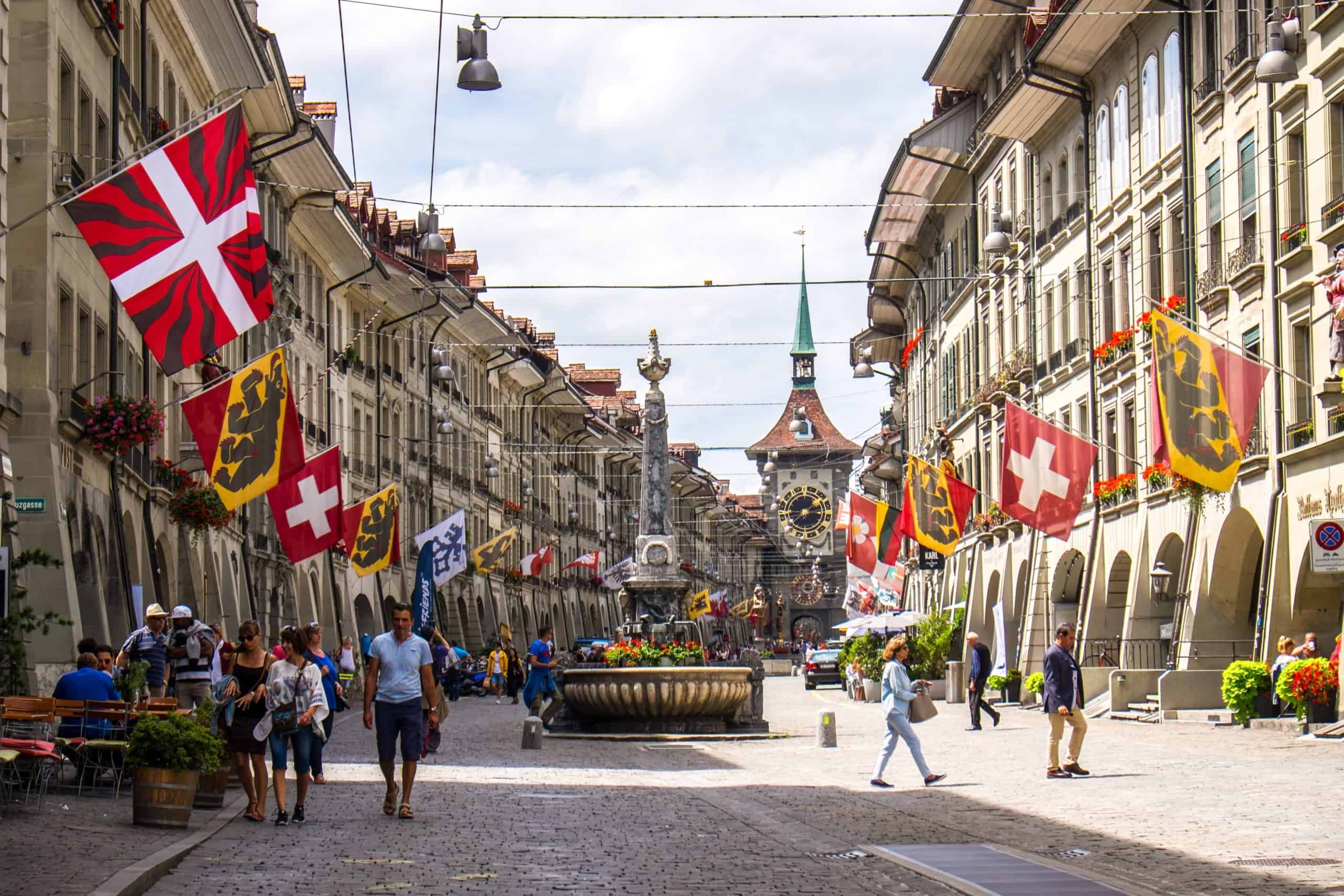 The neat rows of beige coloured arcades in Bern, Switzerland with Swiss and Bear emblem flags flying