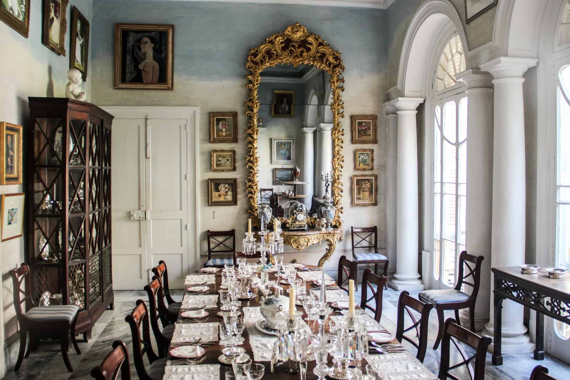 A period furniture dining table, gold gilded mirror, and framed wall artworks in the dining room of Casa Rocca Piccola. 